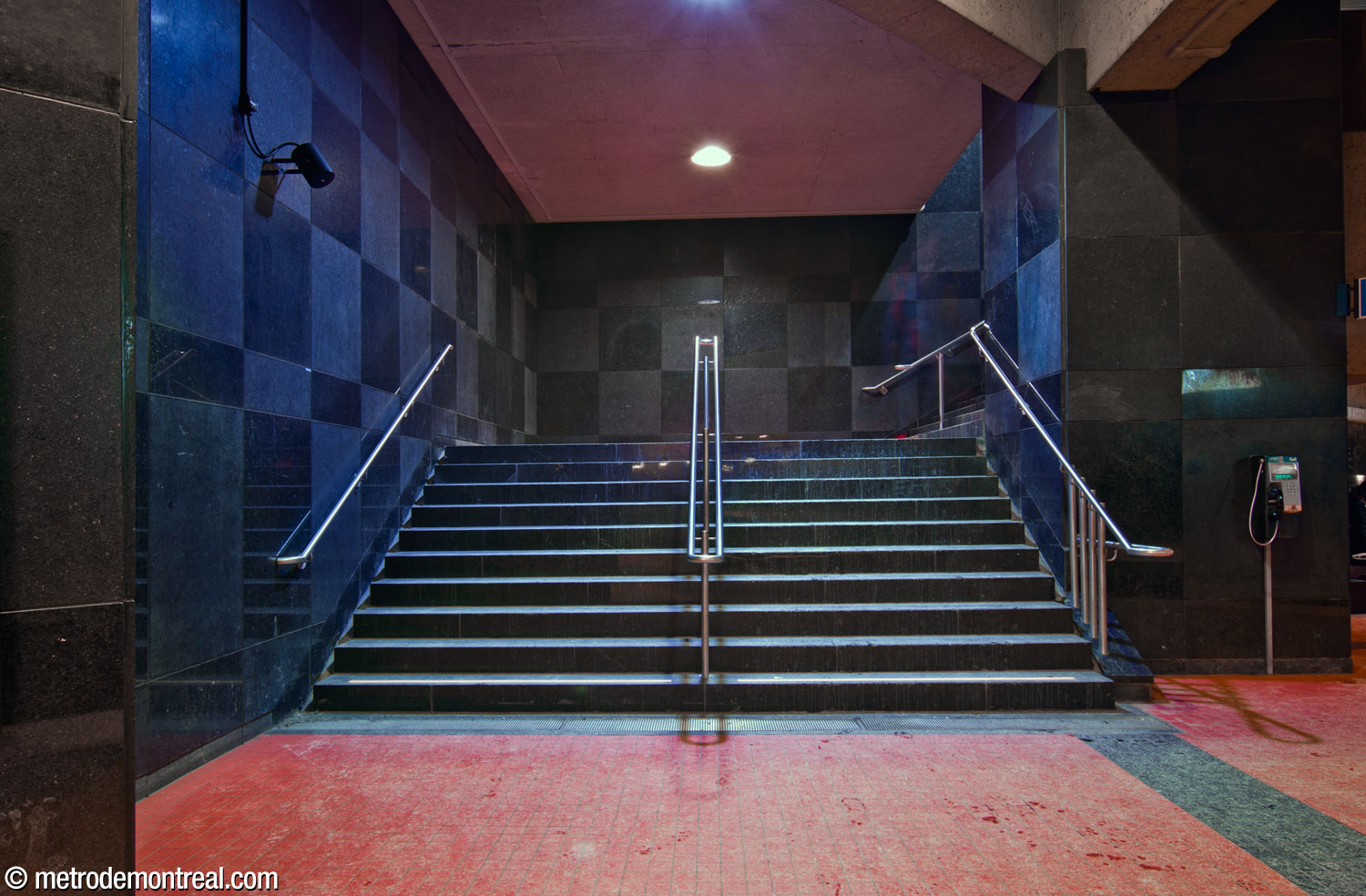 A face-on view of the staircase up from the Saint-Michel platform. The stairwell forms an imposing black cube receding at a 45-degree angle from the platform.