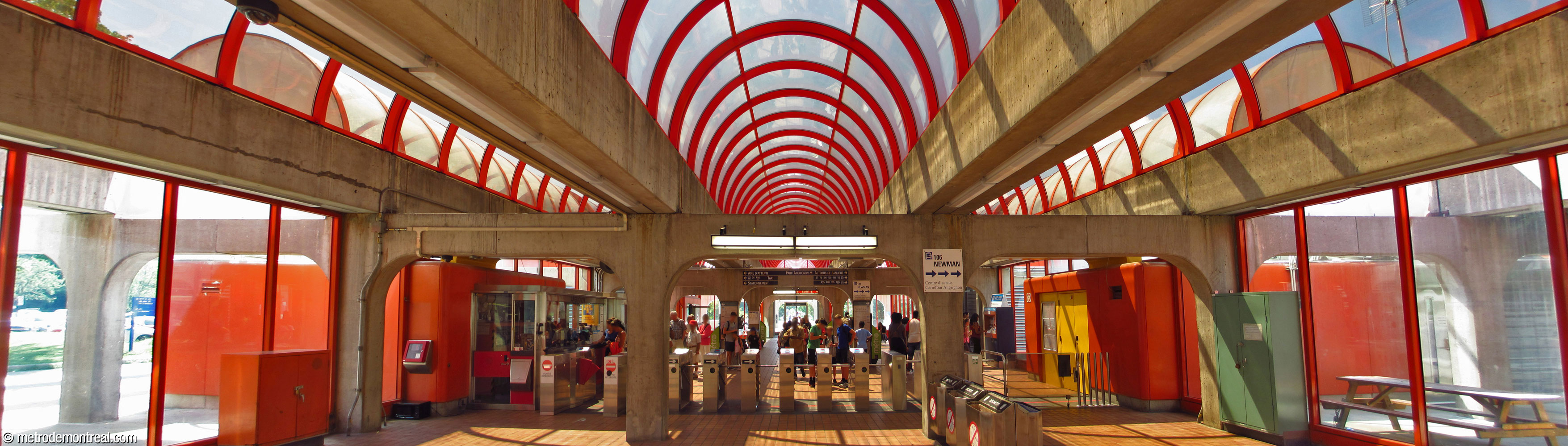 Interior of the station headhouse, showing the turnstiles, framework, and transparent domes above. View from the northeast (inside the fare-paid zone).