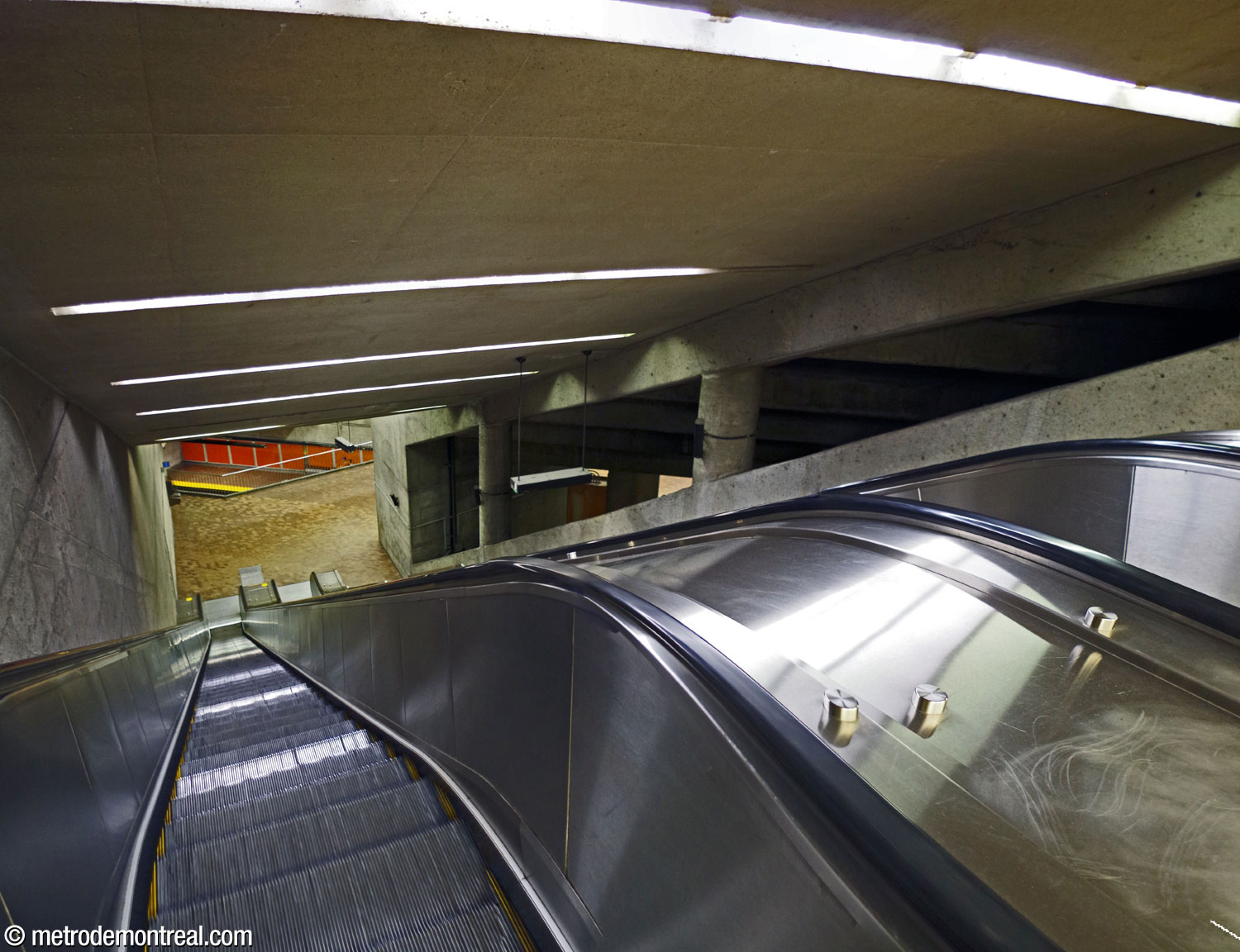 Perspective à partir du sommet des escaliers mécaniques, vers la mezzanine. À droite, l'espace triangulaire surplombant le grand volume. À gauche, le bord de la mezzanine donne sur l'extrémité sud-ouest des quais.