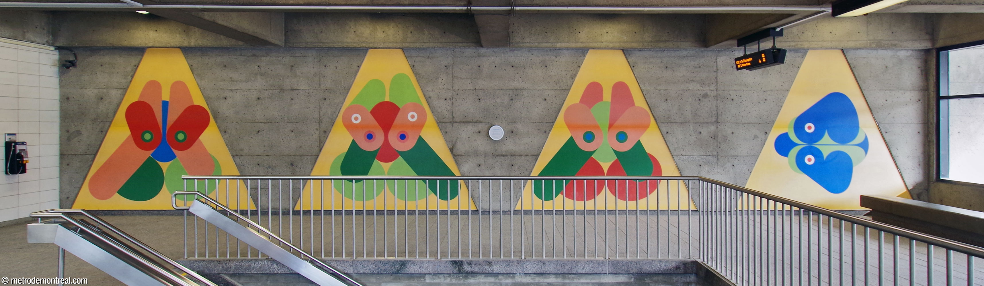 Les quatre éléments de l'ensemble mural Un parcours sur l'olympisme, œuvre de Guy Montpetit, situés dans l'édicule. Les formes trapézoïdales des éléments forment une réflexion des fenêtres du mur en face.