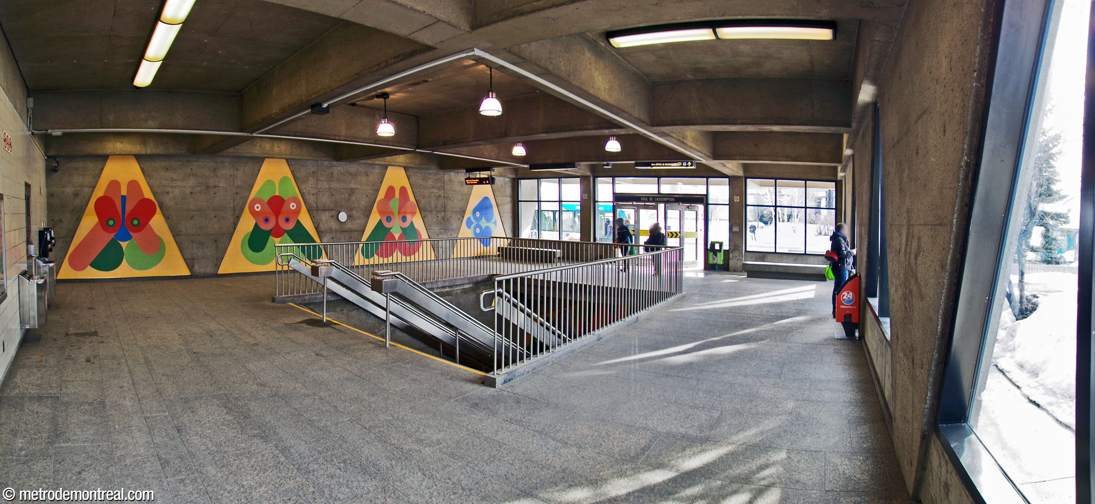 Intérieur de l'édicule de la station. La trémie de l’escalier pour descendre vers la station se trouve au centre de la pièce. Quatre éléments de l'ensemble mural Un parcours sur l'olympisme, œuvre de Guy Montpetit, se trouvent sur le mur sud.