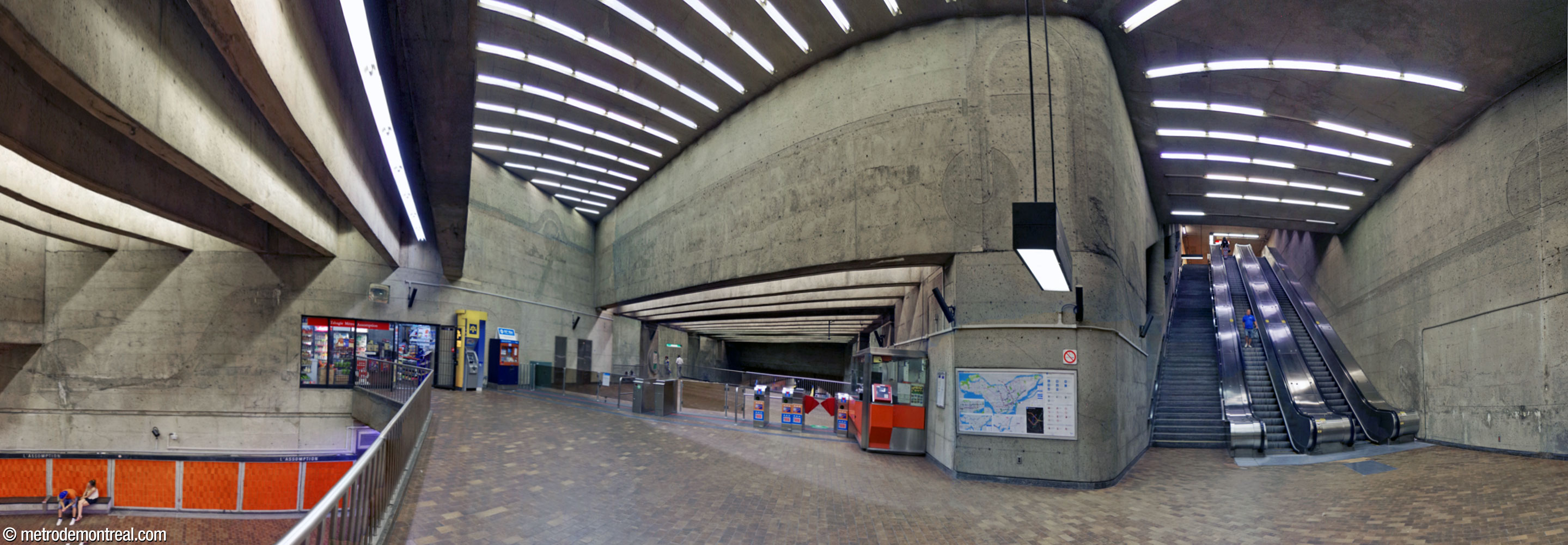 Vue d'ensemble montrant la disposition de la mezzanine. À gauche, un parapet donne sur l'extrémité sud-ouest des quais; à droite, des escaliers mécaniques relient ce niveau à la sortie; au centre, on passe par les tourniquets pour atteindre les escaliers vers les quais. De grands bas-reliefs ornent les parties supérieures des murs.