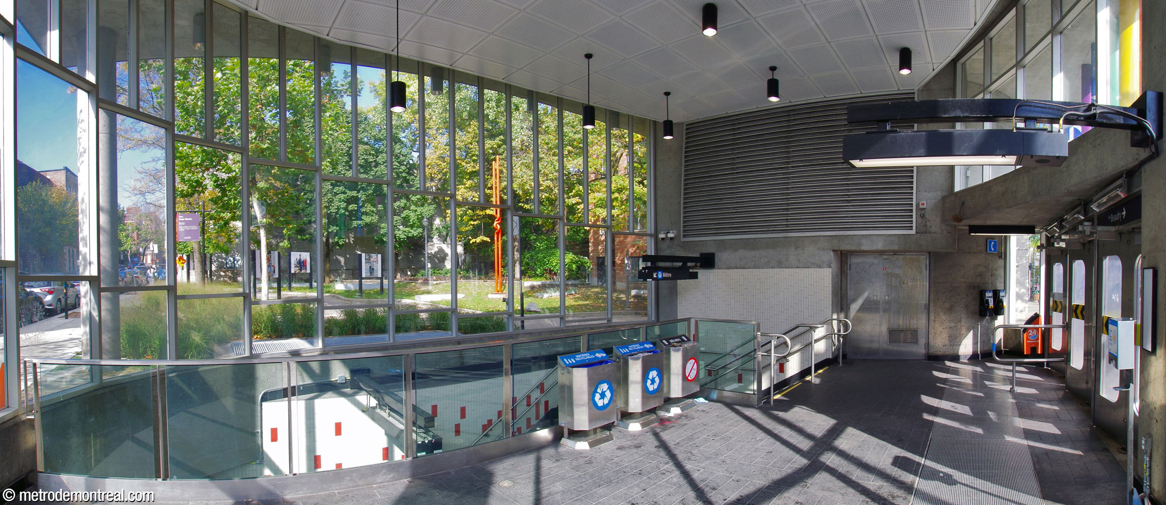 Intérieur de l'édicule; regard sur le petit parc en arrière de la station à travers le large mur-rideau vitré en forme de fer de cheval.
