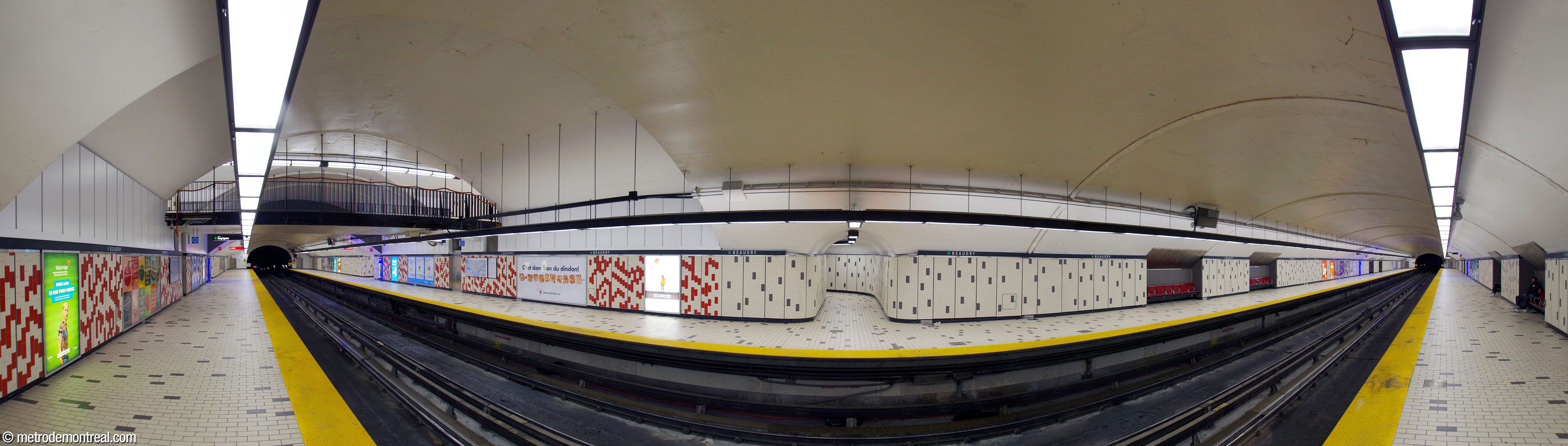 Panorama de la nef creusée en tunnel, vue depuis le quai Angrignon. Le transept, marqué par une voûte surélevée, présente un motif formé de carreaux rouges et couleur crème aux murs; les sections extérieures des quais sont carrelées de couleur crème parsemé de carreaux gris foncé. La passerelle (gauche) traverse l’espace, mais les escaliers qui montent vers elle (dont un au centre) sont contenus dans des couloirs d’accès à part.