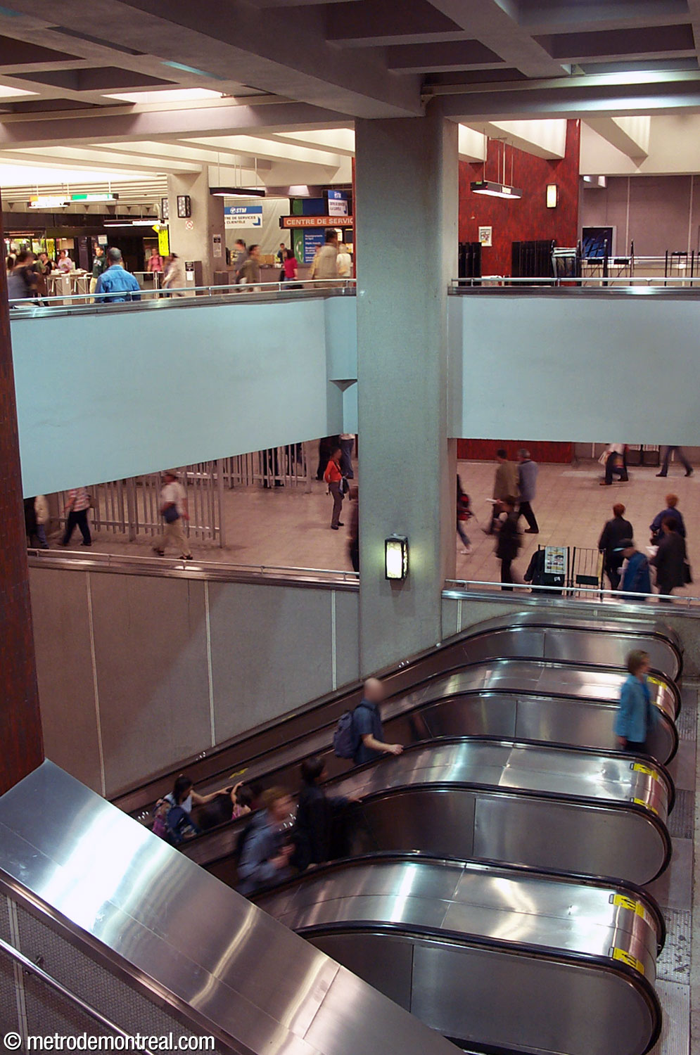 L'un des principaux puits d'escalier en 2003, avant les rénovations de 2010-2021. À noter, les pastilles de céramique grise aux murs, les luminaires distinctifs, le carrelage céramique rouge sur les piliers et les grilles métalliques divisant les paliers de la ligne orange.