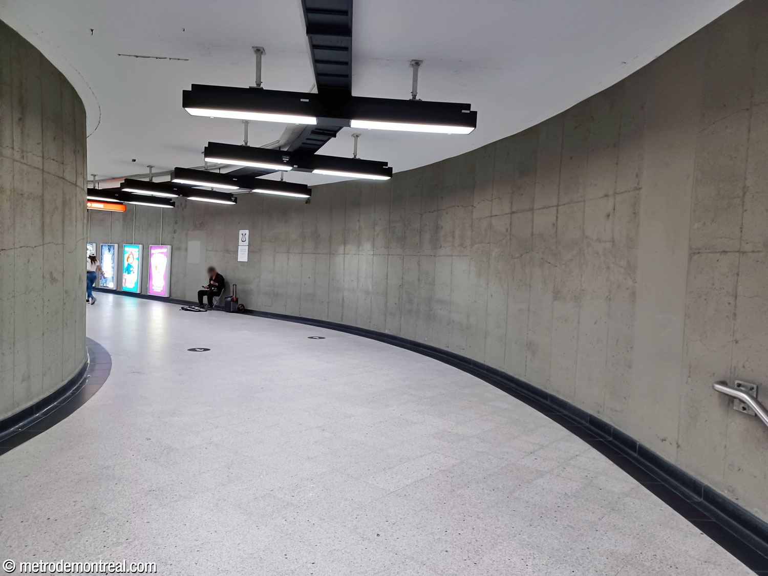Une autre partie du long corridor courbe entre le pied de la volée principale d'escaliers mécaniques vers la ligne jaune et le couloir collecteur menant vers les quais de la ligne jaune.