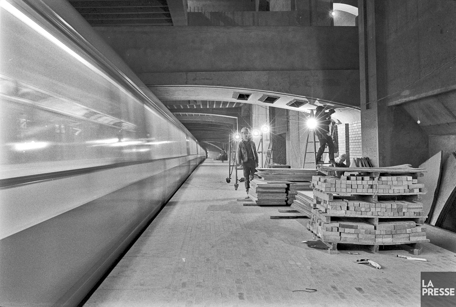 Un quai de la station durant les travaux de finition, peu de temps avant l’ouverture de la station. Un train en essai passe le quai.