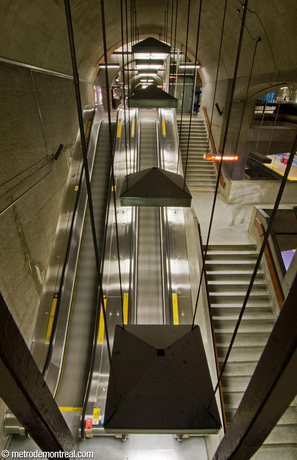 Les passages transversaux aux deux extrémités de la mezzanine présentent d'impressionnantes perspectives des escaliers vers les quais. À droite, le palier de l'escalier fixe est relié à l'une des passerelles permettant de traverser les voies.