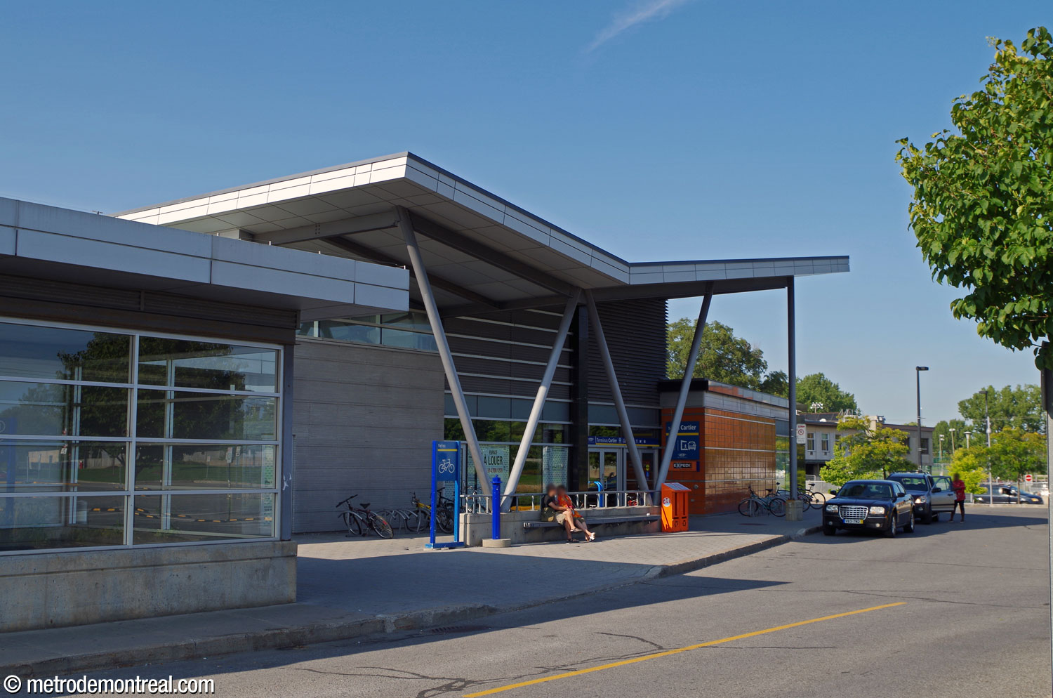 La sortie de l'aile sud de l'édicule vers le stationnement et la jetée sud du terminus d'autobus. À noter le toit papillon de l'aile sud de l'édicule, qui accueille une portion du terminus d'autobus intérieur, et les grandes poutres rondes qui soutiennent la saillie du toit.