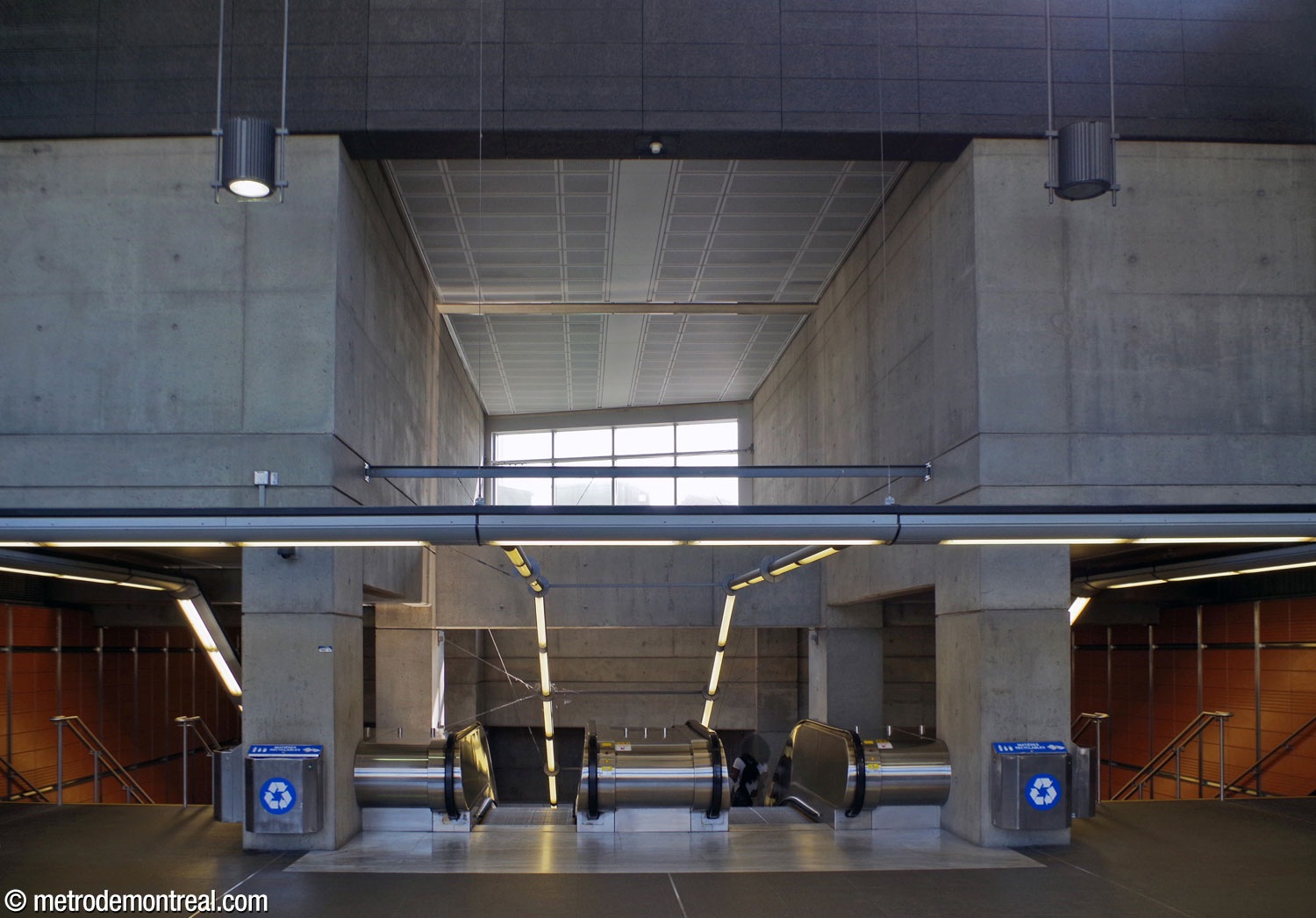 La tête de la large cage d'escalier à partir de la billetterie débouche sur l'atrium surbaissé dans l'édicule principal. Au-dessus des escaliers mécaniques, une claire-voie admet du soleil, en plus de celui admis par le vaste mur de verre en face de ces escaliers (derrière le photographe).