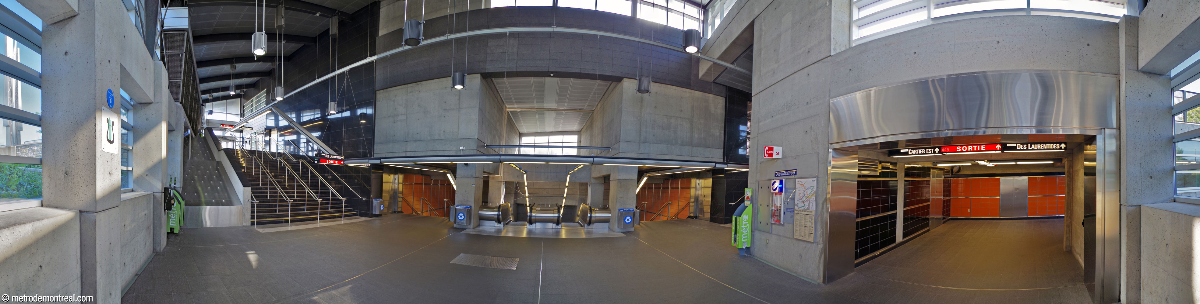 Panorama de l'intérieur de l'édicule. Au centre, les escaliers depuis la billetterie débouchent sur un large atrium surbaissé; de part et d'autre de ce dernier, des escaliers fixes montent vers le niveau de la rue. Celui à gauche donne également accès au terminus d'autobus. Face aux escaliers centraux, un vaste mur de verre (derrière le photographe) éclaire l'espace. À droite, un tunnel mène vers l'édicule secondaire Cartier, en traversant sous le carrefour avoisinant.