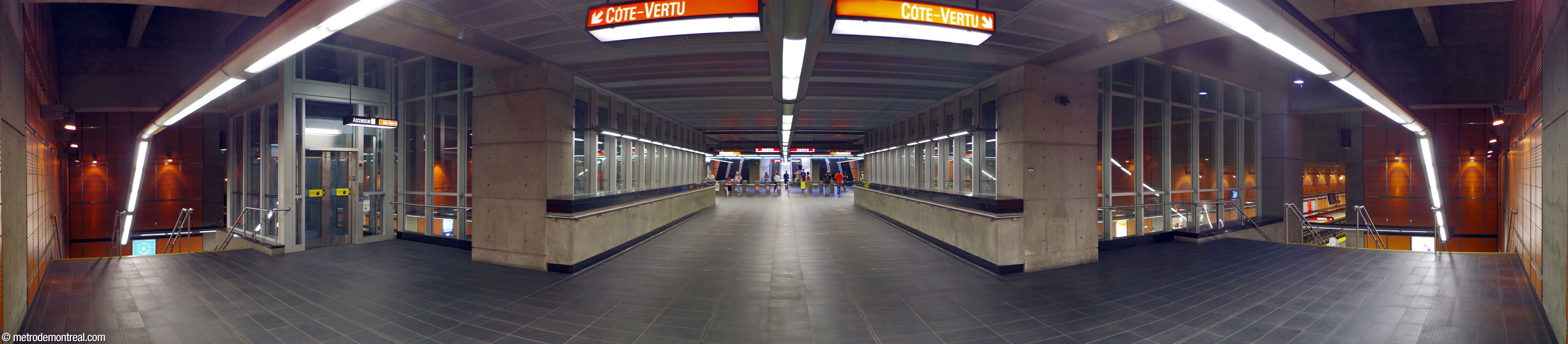 Panorama du transept et de la passerelle au-dessus des voies, enfermée par des murs de verre. L'autre bout de la passerelle rejoint les tourniquets de la billetterie.