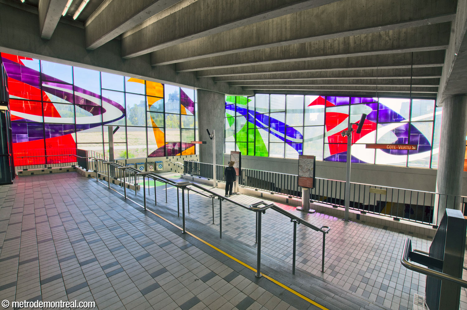 View down the short, broad staircase from street level to the lower level of the ticket hall, overlooking the platforms.