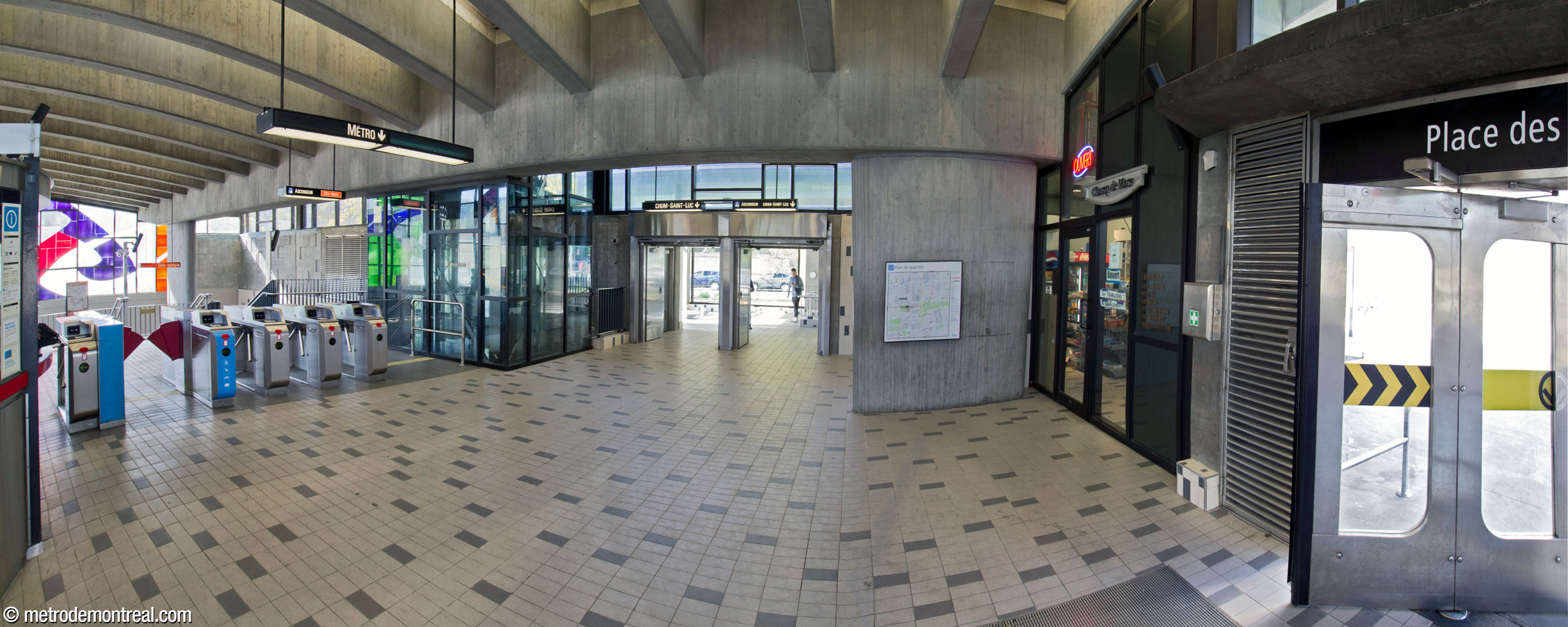 The entrance area of the headhouse outside the ticket barrier, left, looking north. The northern wall of the headhouse is mostly exposed concrete with a plain glass clerestory. At centre, doors lead to the 2014 addition and the underground city link to the CHUM.