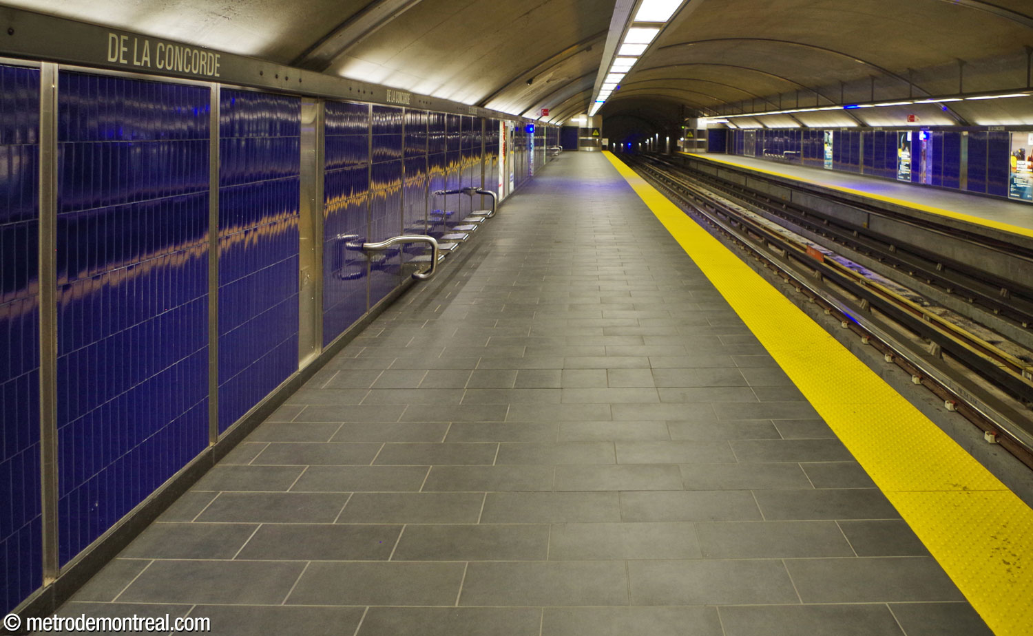 View of the trainroom built in tunnel, looking west from the Côte-Vertu platform. The platform walls are lined with sapphire-blue tiles.