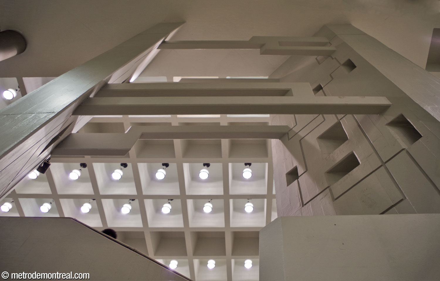 Les piliers jumelés du grand volume et les poutres qui les relient, vus en contre-plongée à partir de l'escalier qu'ils chevauchent.