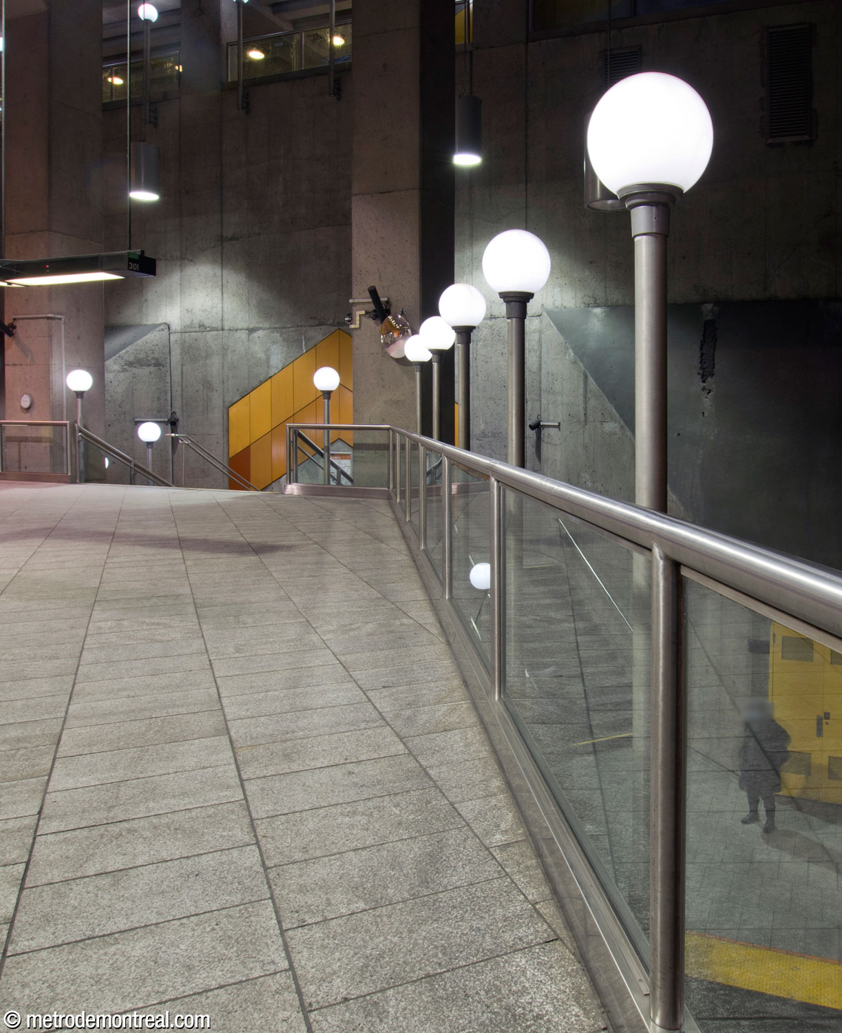 Une ligne des emblématiques luminaires sphériques de la station, le long du parapet de la mezzanine au-dessus des voies.