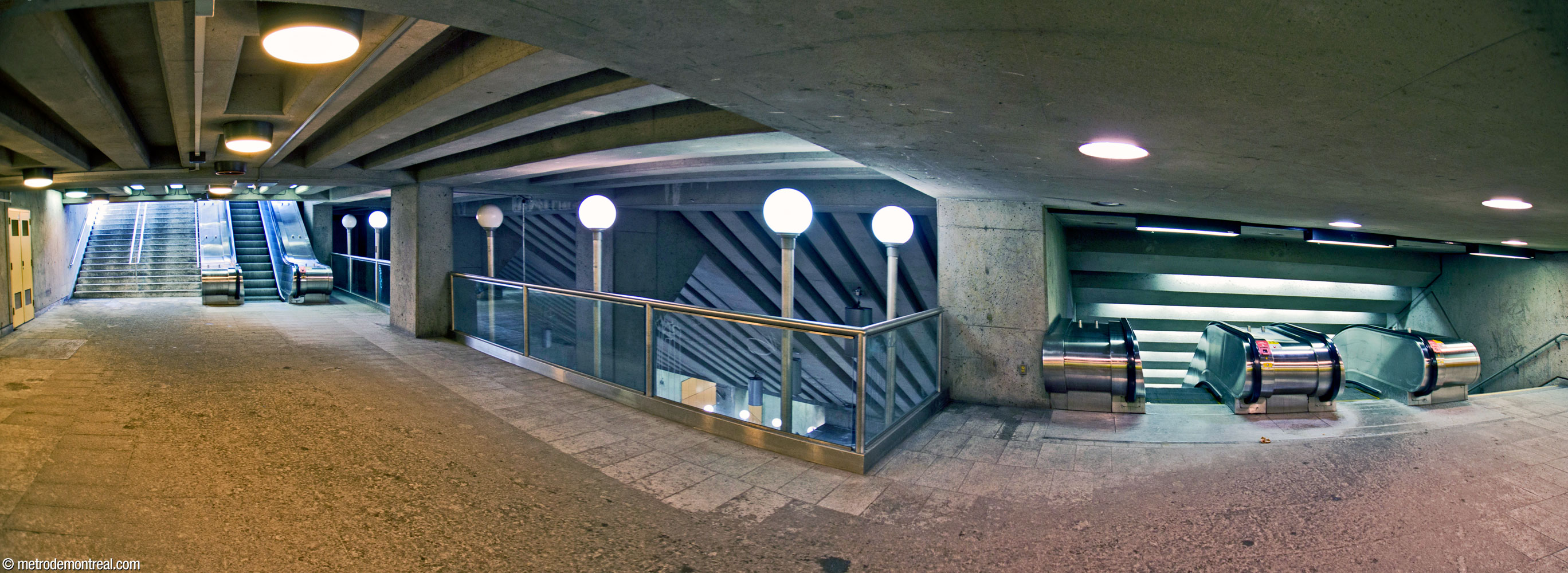 Le passage entre l'édicule (gauche) et les escaliers mécaniques vers la mezzanine (droite) surplombe le grand volume de la station.
