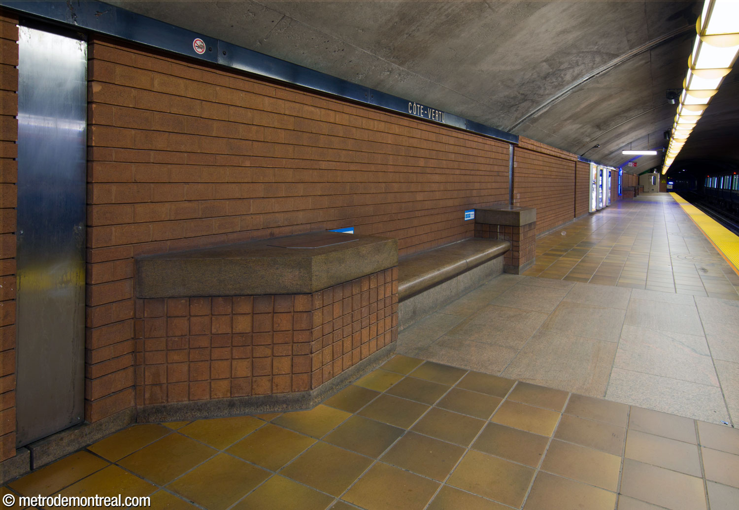 L'un des bancs au niveau des quais, entouré par les finitions de la station : carrelage mural en terre cuite, granit et grès au sol.