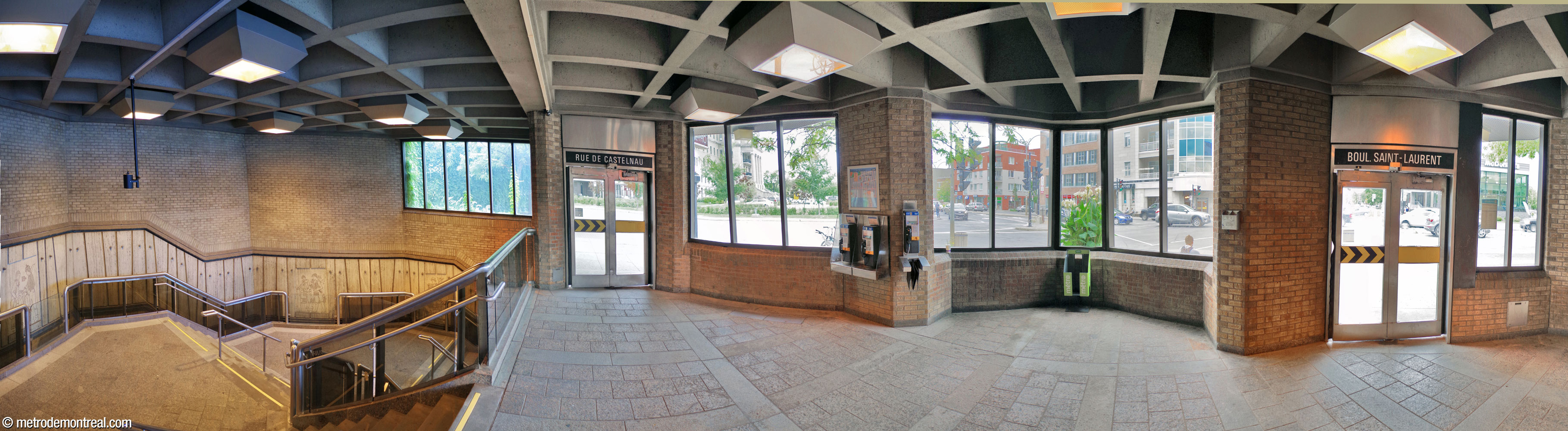 Panorama of the interior of the Saint-Laurent Ouest headhouse. The roof features deep square coffers. The entrances lead to a landing over a U-shaped staircase leading to the ticket hall. The stairs are lined by travertine dadoes, like the ones on the platform level, which feature bas-reliefs by Jean-Charles Charuest.