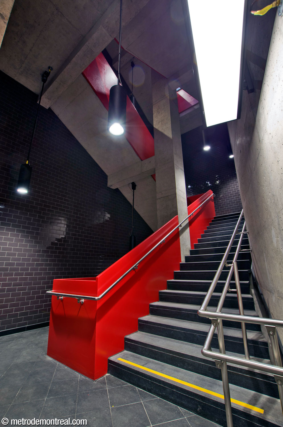 L’escalier auxiliaire accompagnant l’ascenseur principal est encadré par une balustrade écarlate vif et des murs d’accent noir. On regarde vers le haut à partir du niveau du transept.