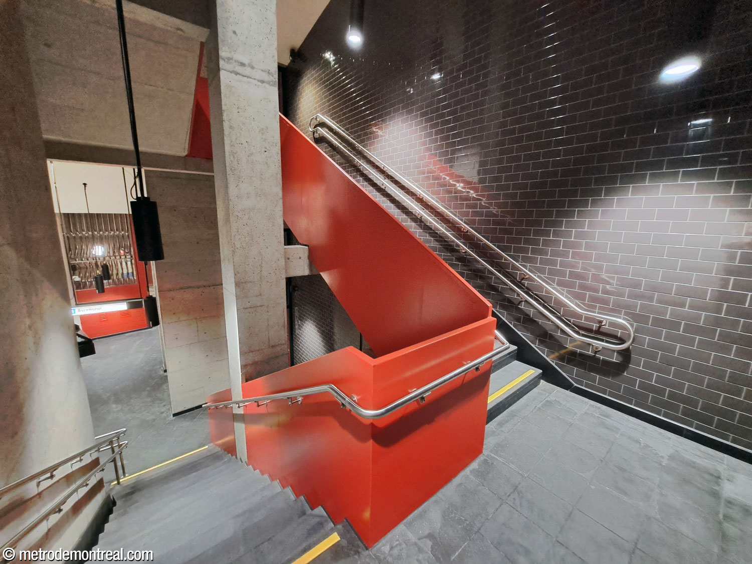 L’escalier auxiliaire accompagnant l’ascenseur principal est encadré par une balustrade écarlate vif et un mur d’accent noir. On regarde vers le bas depuis le palier en haut du niveau du transept.