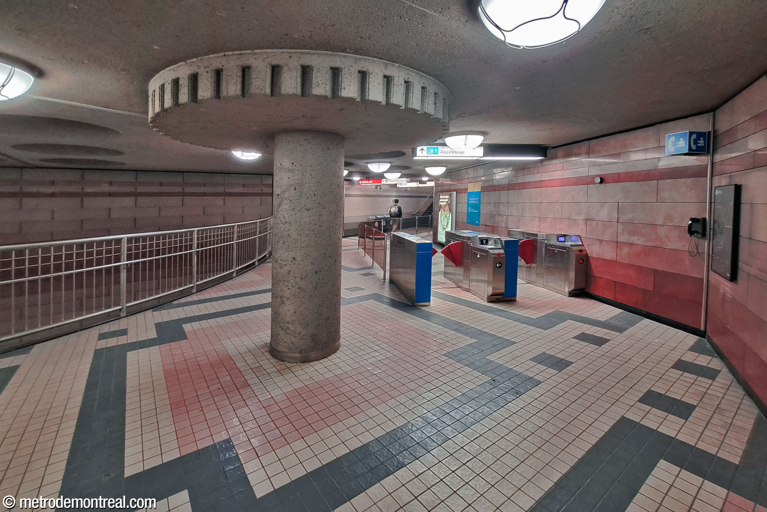 Le corridor entre la billetterie et l'accès Édouard-Montpetit/CEPSUM passe un parapet (gauche) qui donne sur la cage d'escalier vers le niveau du transept. La barrière de perception secondaire ici donne accès à l’ascenseur principal.