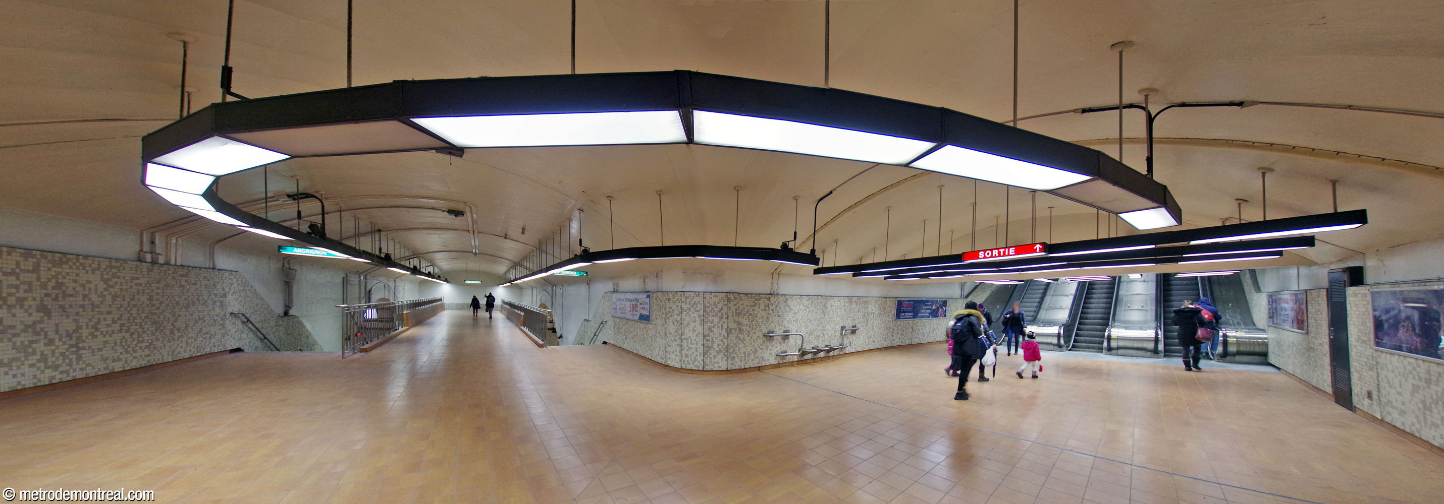 La forme courbe du couloir reliant le pied des escaliers mécaniques avec le transept et la passerelle.