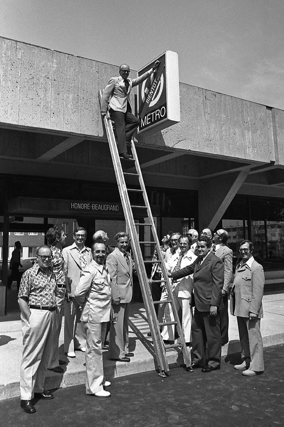 Le président de la CTCUM, Lawrence Hanigan, enlève un autocollant marqué « Bientôt! » de l’enseigne du métro lors de la mise en service de la station, le 6 juin 1976.