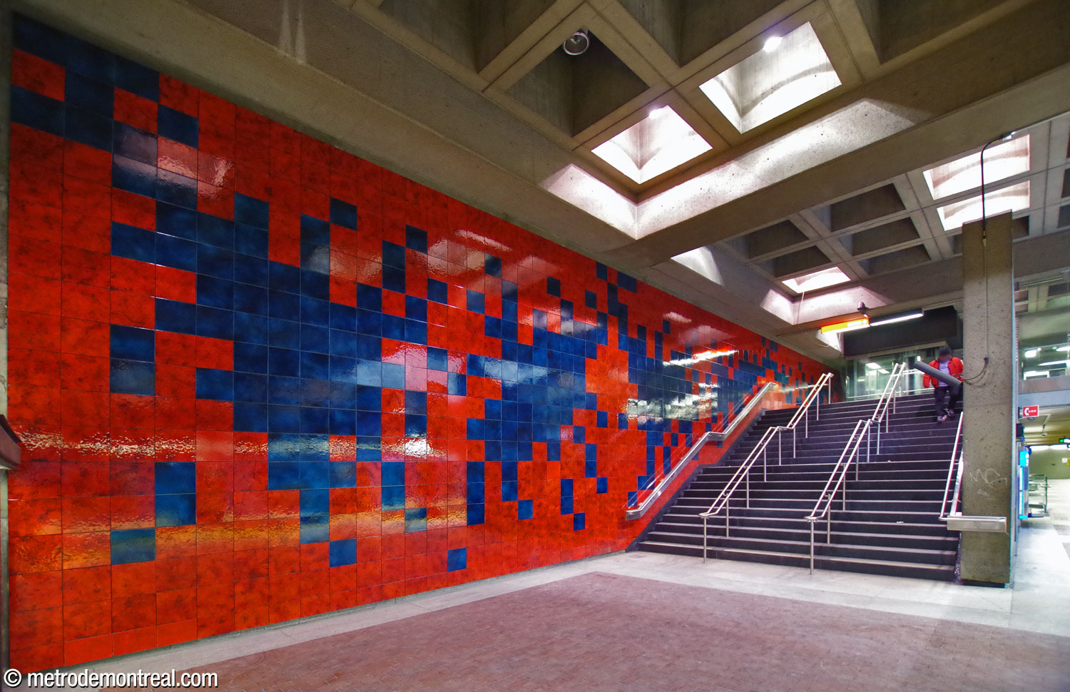 Murale en céramique de Jean-Paul Mousseau, avec des formes bleues sur un fond rouge, longeant l'escalier vers le quai de départ.
