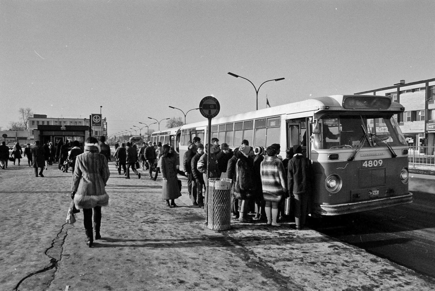 Des passagers montent dans un autobus sur le boulevard Henri-Bourassa, près de l'édicule nord du terminus d'autobus.
