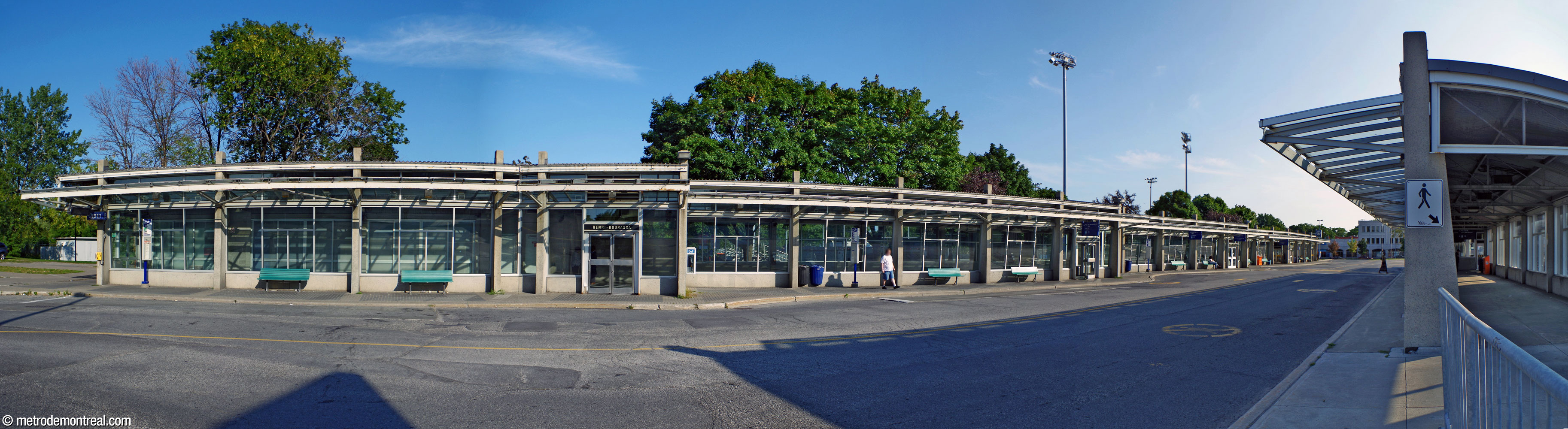 Vue d'ensemble du long édicule sud du terminus d'autobus Henri-Bourassa Sud. Le bâtiment, construit de verre, béton et acier, longe le côté sud de la boucle. On voit également l'édicule de l'îlot nord, à droite.