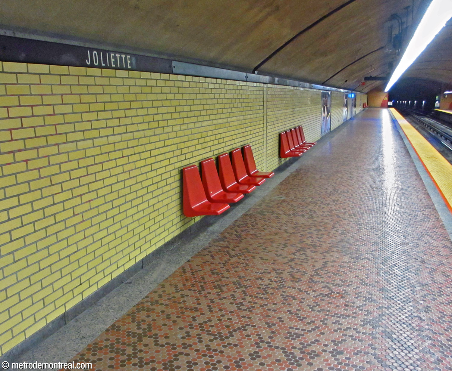 La brique jaune unie et le carrelage circulaire au sol en tons de brun, au niveau des quais.