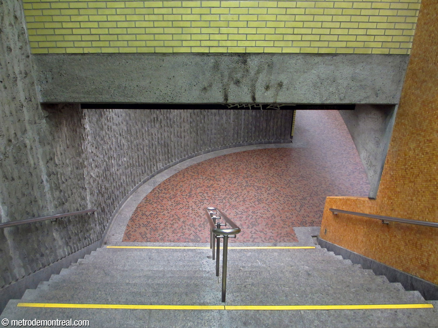 Vue en plongée d'une cage d'escalier menant au quai Angrignon. Le mur extérieur est revêtu de béton cannelé.