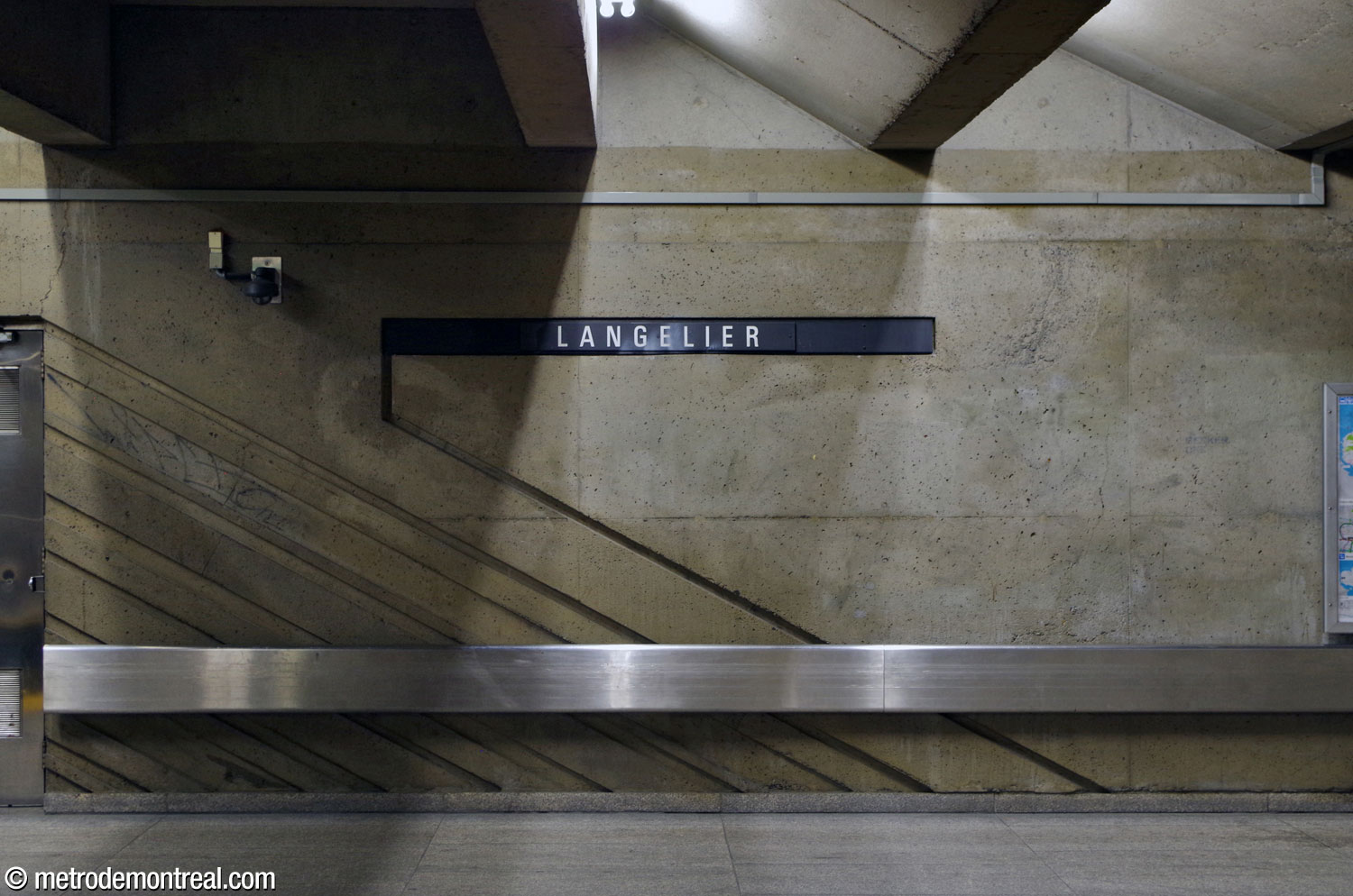 Une rayure oblique en bas-relief au niveau du mur central rejoint l'un des bandeaux d'identification de la station.