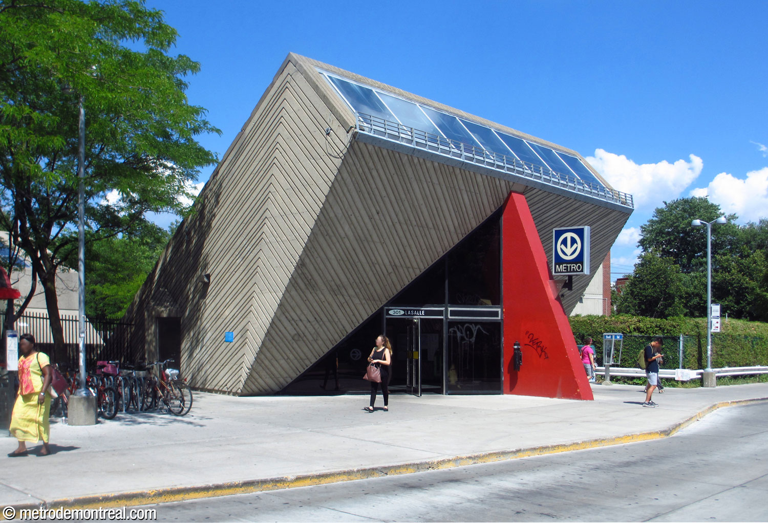 An oblique view of the station's headhouse. The mass of the headhouse thrusts up diagonally from the ground and features clerestory windows on its front edge.