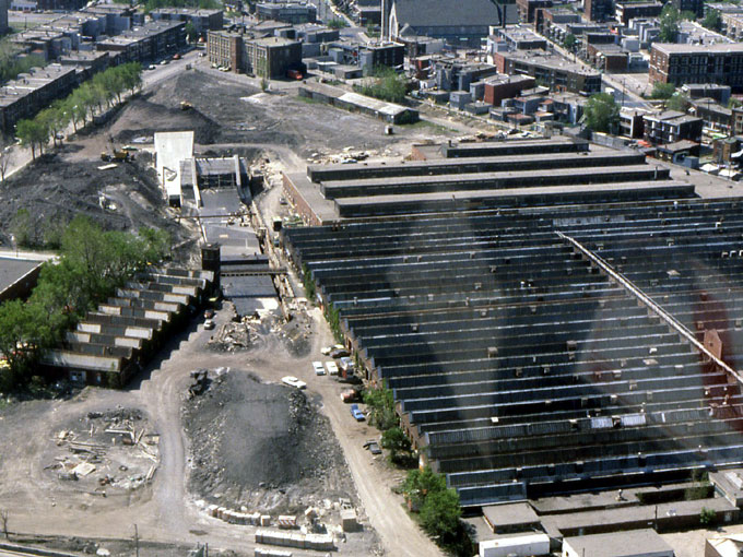Aerial view of the area during station construction; the former munitions factories are seen behind and to the right of the station.