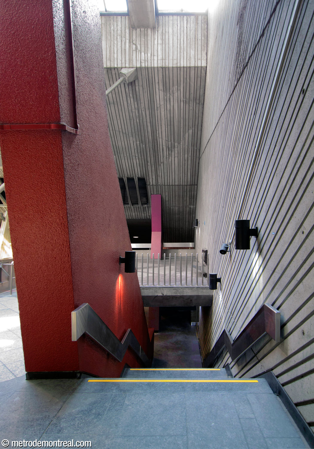 One of the stairwells toward the Angrignon platform, marked by a red concrete form that visually links the platform and mezzanine.