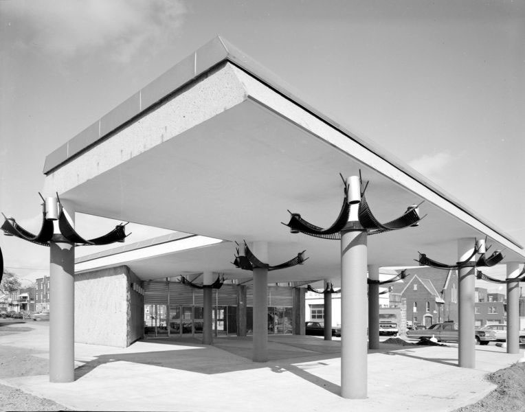 Une colonnade avec d'impressionnants lampadaires sous le vaste auvent constitué par la saillie du toit de l'édicule Saint-Joseph, vue ici du sud-ouest. Cette photo a été prise avant le prolongement de l'auvent pour protéger les arrêts d'autobus le long de la rue Gilford.