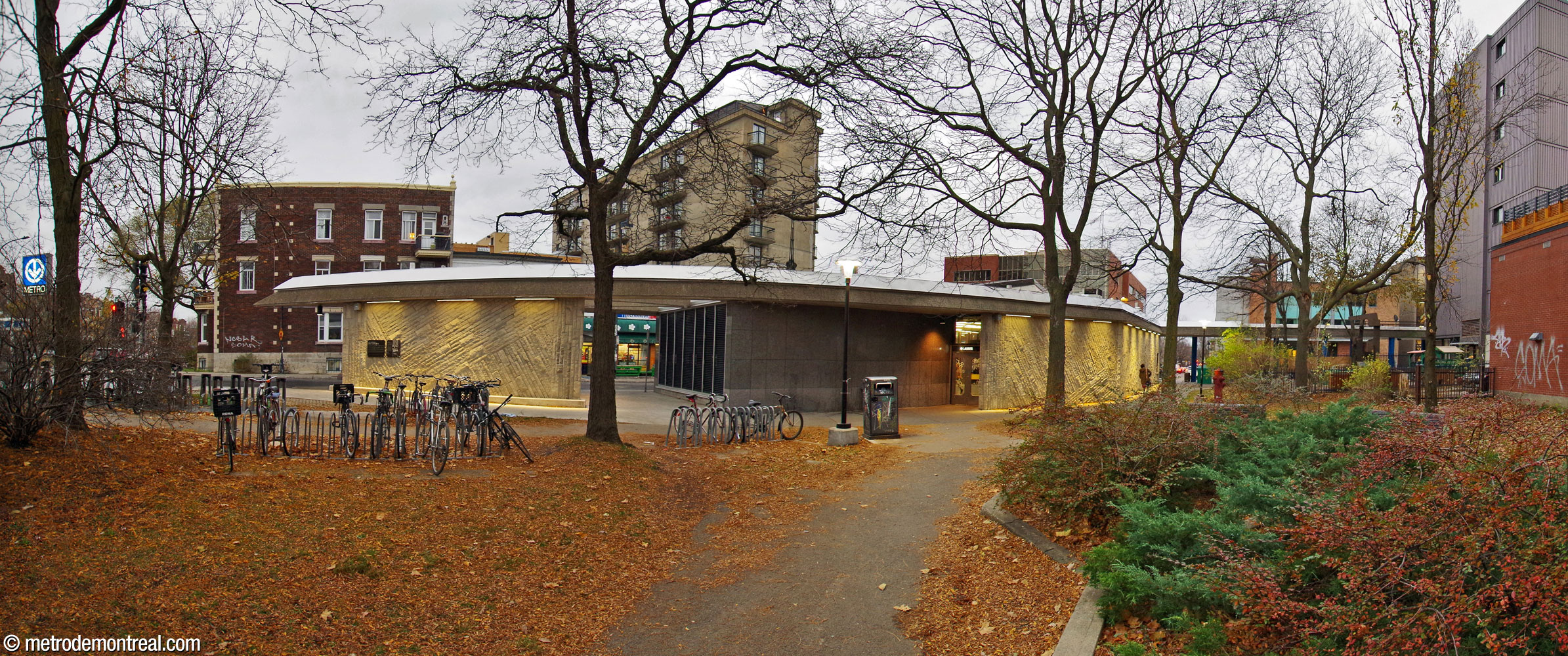 L'édicule Saint-Joseph vu depuis le parc attenant. À gauche, un puits de lumière constitue la pointe de la forme de fer de lance de l'édicule. Ce puits est pratiquement isolé sauf pour les poutres de la toiture qui le relient à l'autre partie. L'édicule possède une seule porte de ce côté. Au sud (droite), la toiture se poursuit le long de la boucle d'autobus pour offrir une aire d'attente protégée.