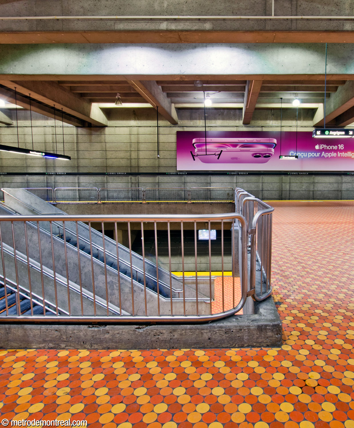 Regard le long de l’une des ouvertures au centre du quai supérieur, qui sert de trémie d’escalier tout en offrant des perspectives sur le quai inférieur et articulant les surfaces et les volumes de la station.