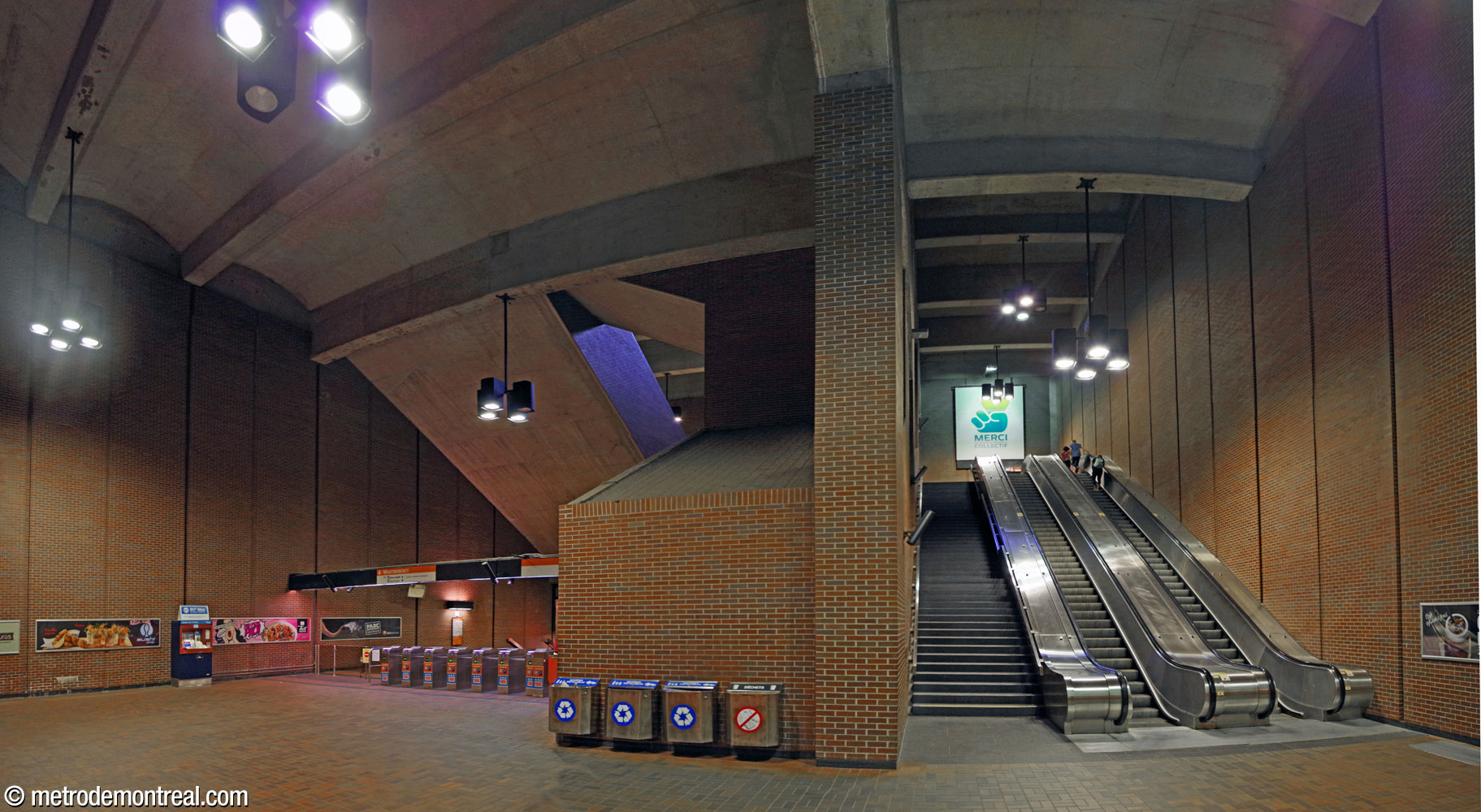 The ticket hall level and the volume overhead, seen from the foot of the escalators heading up.