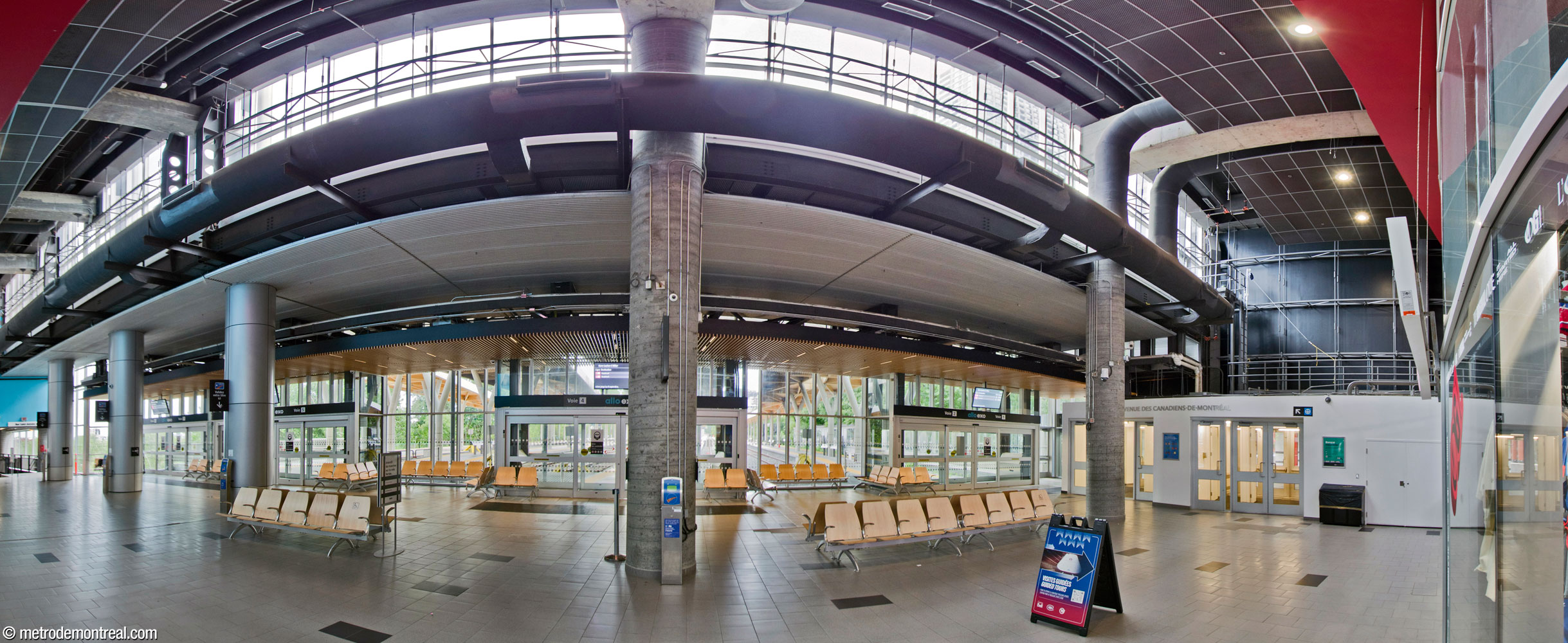 Panorama of the interior of the commuter train station, on the ground floor of the Bell Centre, facing the sliding doors leading out to the platforms. The exit to Avenue des Canadiens-de-Montréal and the connection to the metro station are at right; the exit to Rue Saint-Antoine is at left.