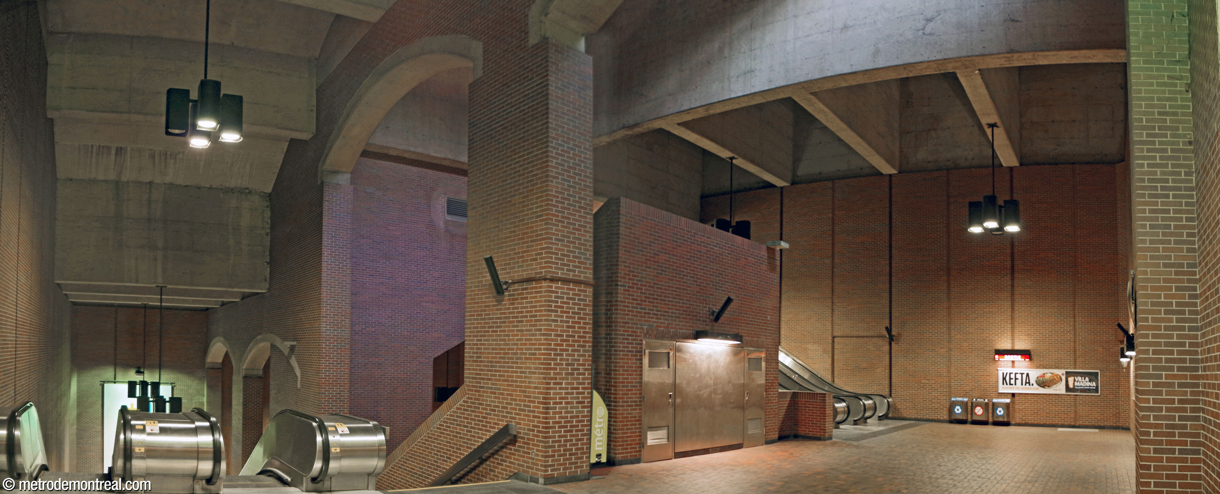 Panorama of the second landing and the towering volume above it. At left, a row of massive arches separates the escalator well between this landing and the ticket hall level.