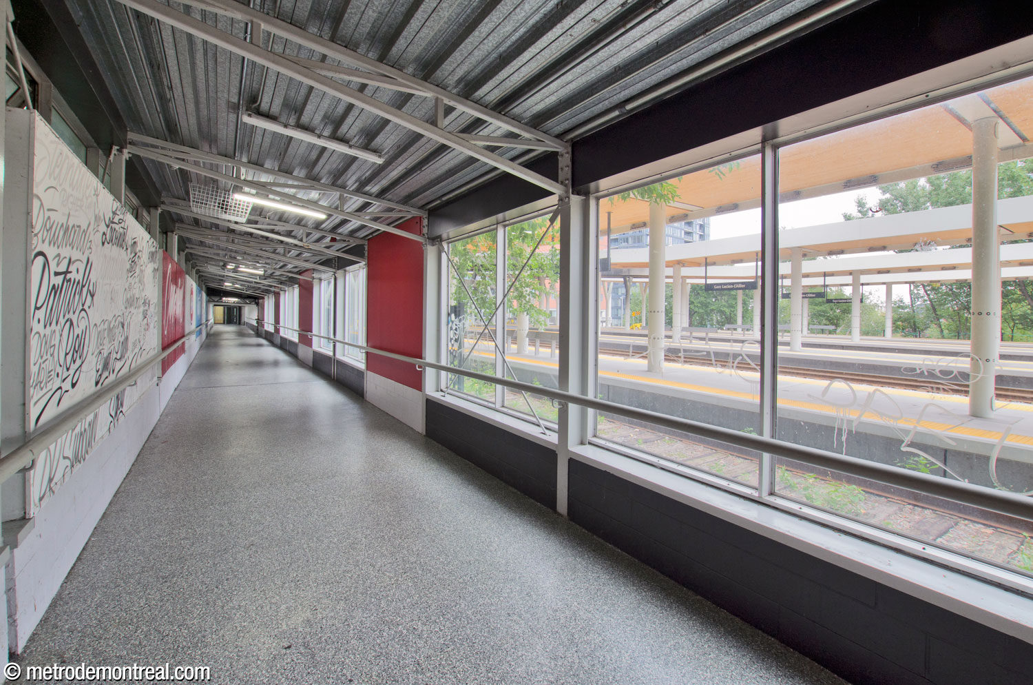 The above-ground connection between the metro and commuter train stations runs along and overlooks the train tracks (right). A mural by Cam Harapiak runs along the wall (left).