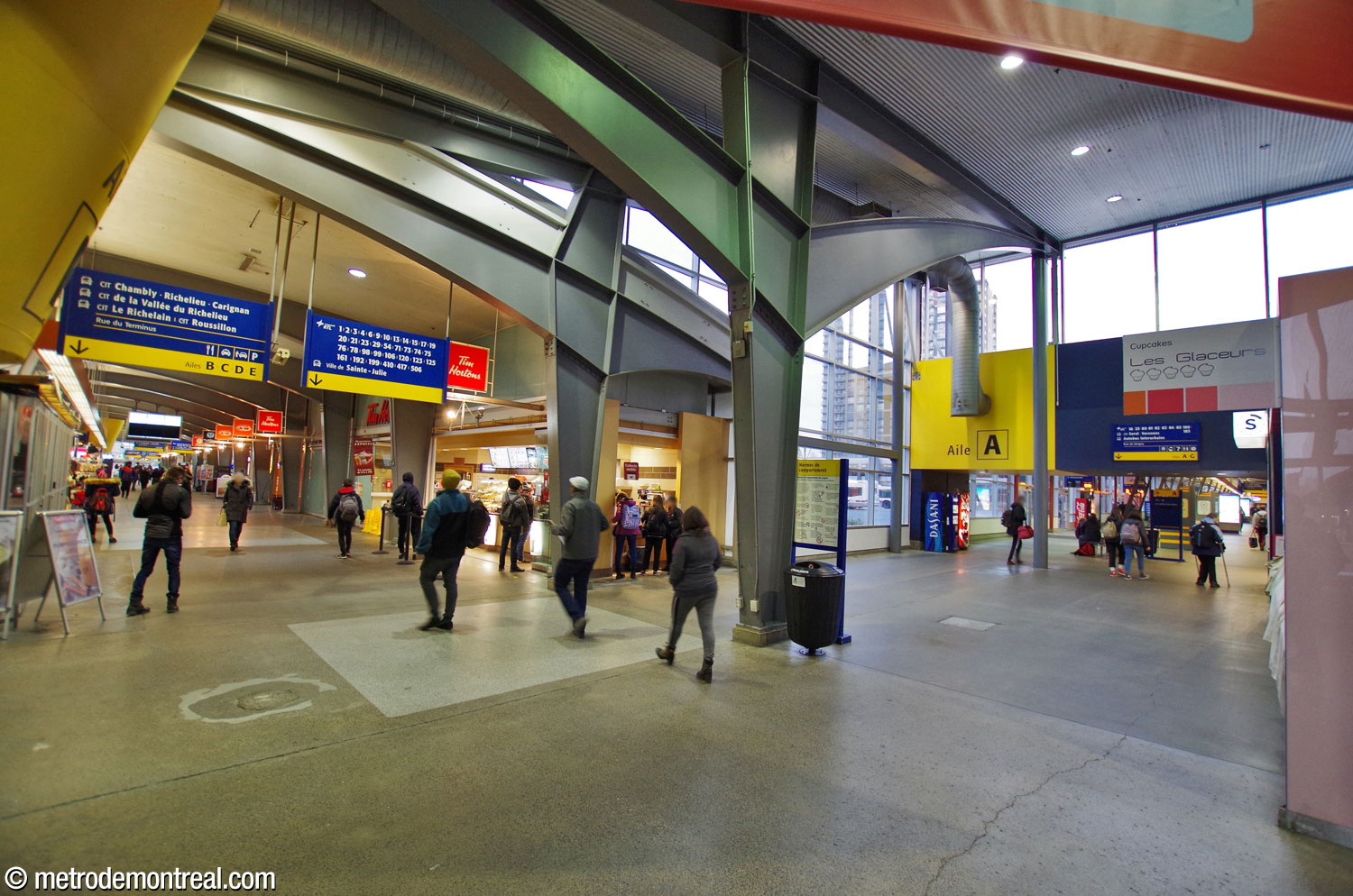 Interior of the bus terminal. The A wing (right), which contains the ticket hall, runs alongside the building that houses the metro entrance. At left, the central passageway, lined with shops and restaurants, extends southward, branching out into enclosed bus platforms on either side.