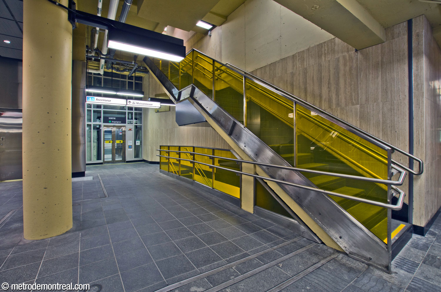 The elevator between the surface and the Angrignon platform is accompanied by narrow staircases up to the 705 De Maisonneuve Ouest headhouse and down to the landing and small gateline at the foot of the elevator at platform level.