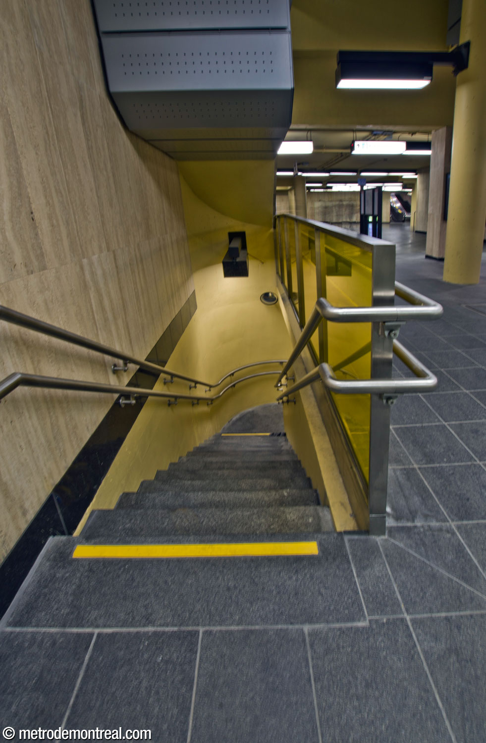 The narrow staircase leading down to the small landing and gateline at the head of the Angrignon platform.