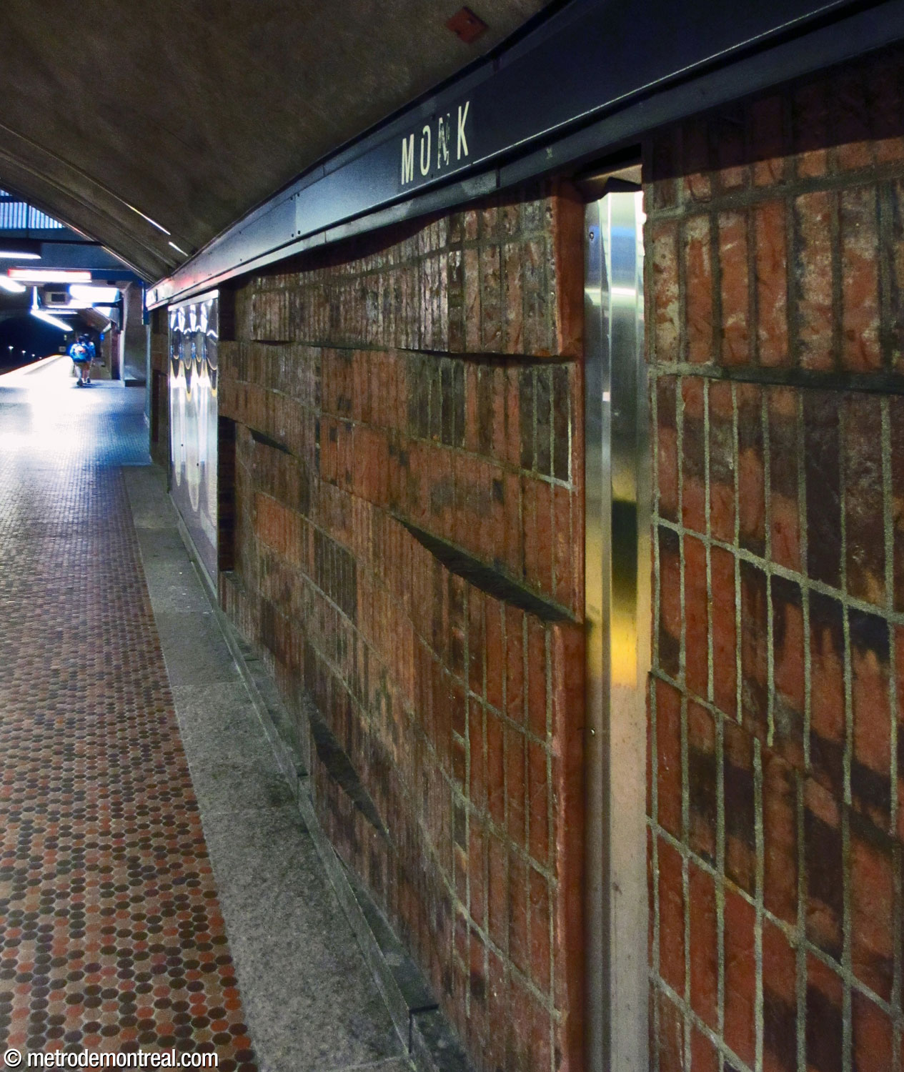Undulating brown brick cladding and small, circular brown floor tiles at platform level.