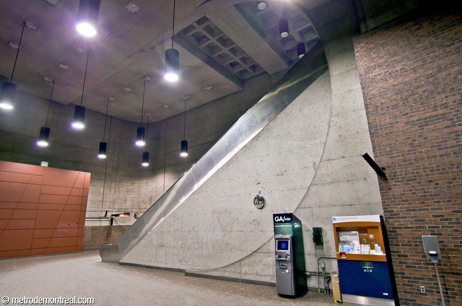 The broad arc that sets off the diagonal line of the escalator in the ticket hall.